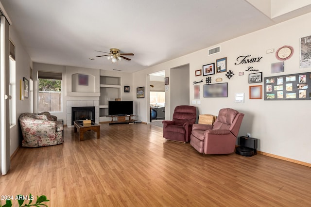 living room featuring ceiling fan, hardwood / wood-style flooring, and a fireplace