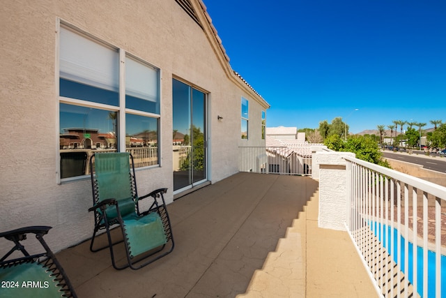 view of patio featuring a balcony and a swimming pool