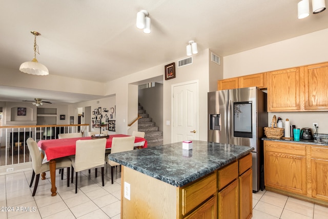 kitchen featuring hanging light fixtures, light tile patterned flooring, a kitchen island, ceiling fan, and stainless steel refrigerator with ice dispenser