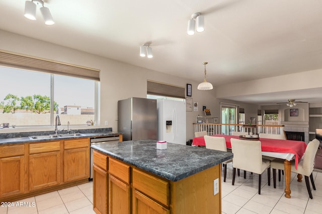 kitchen featuring ceiling fan, pendant lighting, sink, a tiled fireplace, and a center island