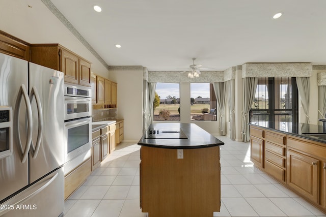 kitchen featuring stainless steel appliances, a kitchen island, light tile patterned floors, and ceiling fan