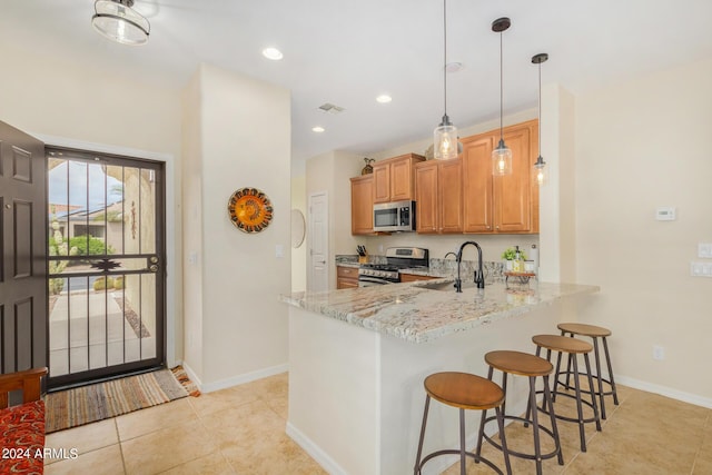 kitchen featuring light tile patterned floors, appliances with stainless steel finishes, decorative light fixtures, light stone counters, and kitchen peninsula