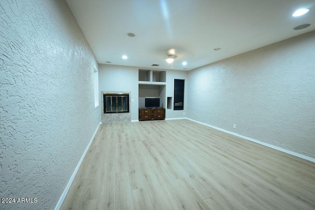 unfurnished living room featuring light wood-type flooring and built in features