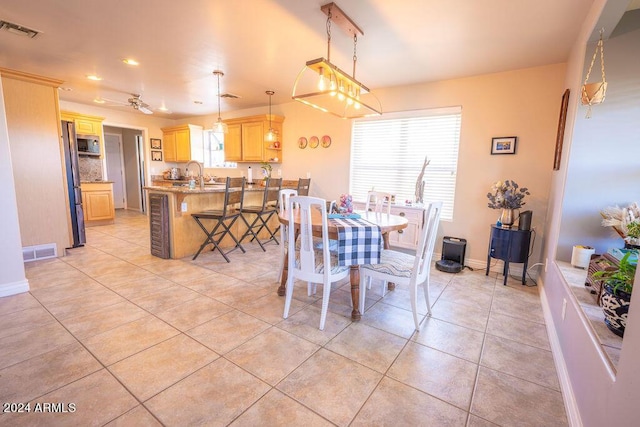 tiled dining room featuring ceiling fan and sink