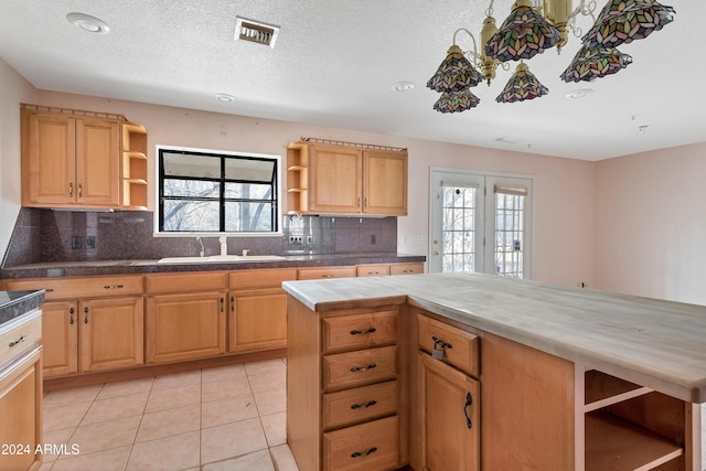 kitchen with tasteful backsplash, plenty of natural light, light tile patterned floors, and sink