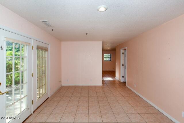 unfurnished room featuring light tile patterned flooring and a textured ceiling