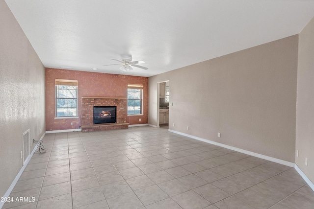 unfurnished living room with ceiling fan, light tile patterned floors, and a brick fireplace