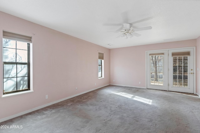 carpeted empty room with a wealth of natural light and ceiling fan