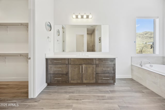 10540 S 32nd Dr, Laveen, AZ 85339 - bathroom featuring vanity, a bath, a spacious closet, and wood finished floors