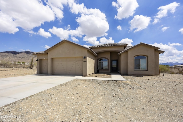 10540 S 32nd Dr, Laveen, AZ 85339 - mediterranean / spanish home featuring an attached garage, stucco siding, a mountain view, concrete driveway, and a tiled roof