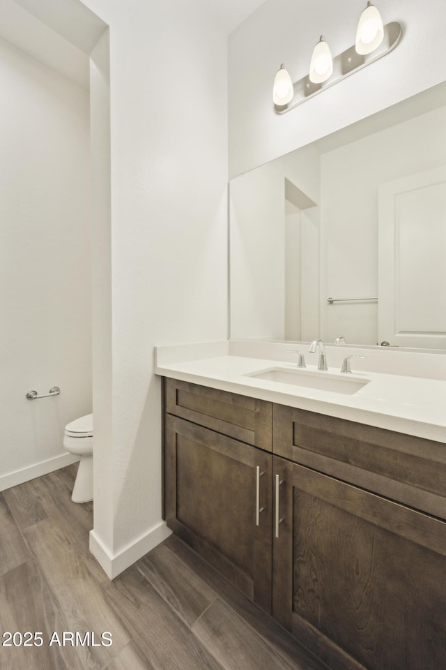 10540 S 32nd Dr, Laveen, AZ 85339 - bathroom with wood finished floors, toilet, vanity, and baseboards