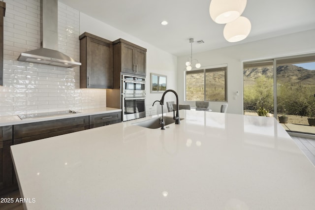10540 S 32nd Dr, Laveen, AZ 85339 - kitchen featuring wall chimney range hood, stainless steel double oven, a sink, light countertops, and dark brown cabinetry