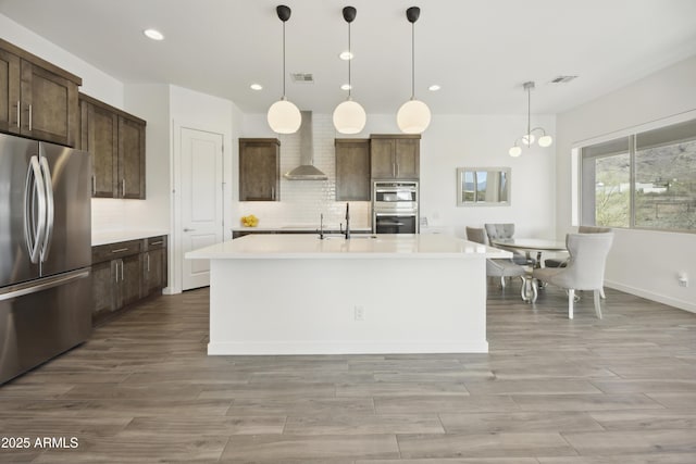 10540 S 32nd Dr, Laveen, AZ 85339 - kitchen featuring stainless steel appliances, light countertops, recessed lighting, tasteful backsplash, and wall chimney range hood