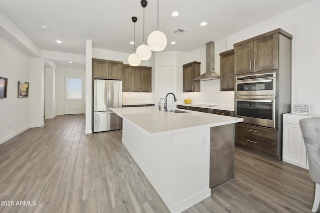 10540 S 32nd Dr, Laveen, AZ 85339 - kitchen featuring appliances with stainless steel finishes, wall chimney range hood, a sink, light countertops, and tasteful backsplash