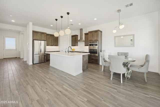 10540 S 32nd Dr, Laveen, AZ 85339 - kitchen with appliances with stainless steel finishes, wall chimney range hood, a sink, light countertops, and light wood-type flooring