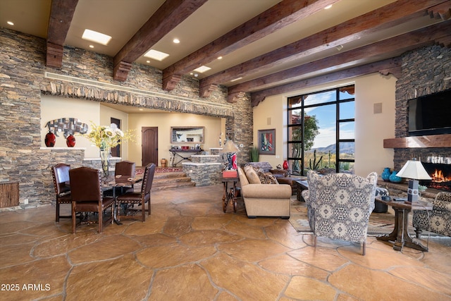 interior space featuring a warm lit fireplace, beamed ceiling, and stone flooring