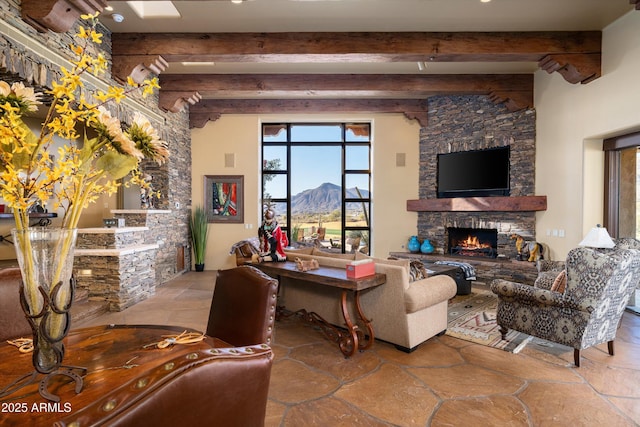 living area featuring beamed ceiling, a fireplace, and stone tile flooring