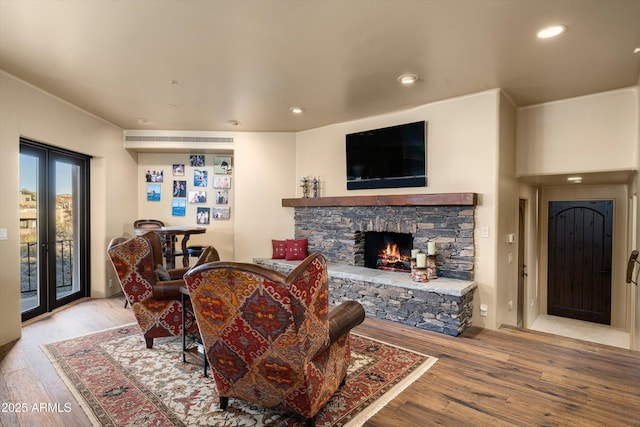 living area featuring light wood-style floors, recessed lighting, french doors, and a fireplace