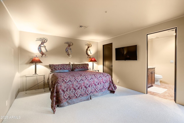 bedroom with visible vents, light carpet, and ensuite bathroom