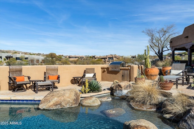 view of swimming pool featuring grilling area, an outdoor kitchen, a fenced in pool, and a patio