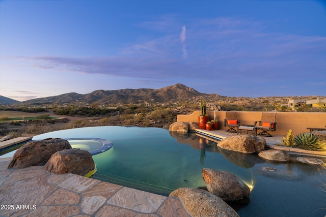 pool at dusk featuring a mountain view, a patio, and an in ground hot tub