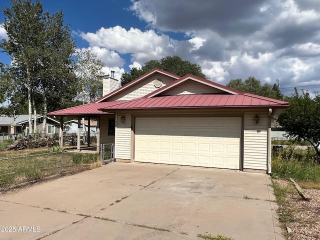 view of front of property featuring metal roof, a garage, fence, concrete driveway, and a chimney