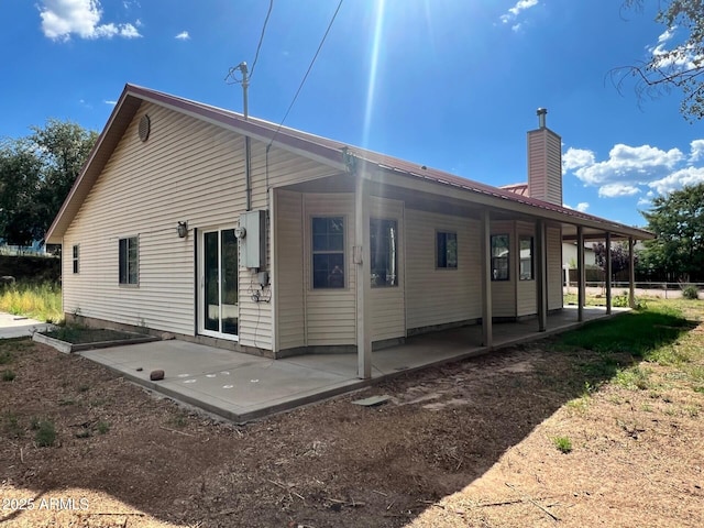 back of property featuring a chimney and a patio area