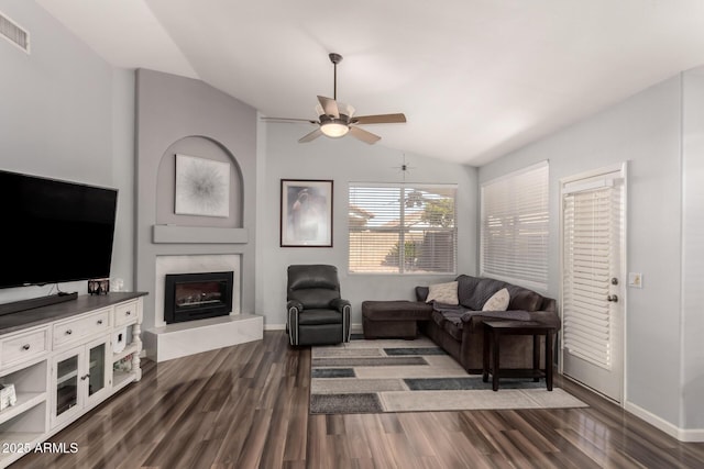 living room with ceiling fan, dark wood-type flooring, a high end fireplace, and vaulted ceiling