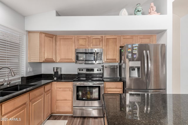 kitchen featuring appliances with stainless steel finishes, light brown cabinets, dark stone counters, and sink