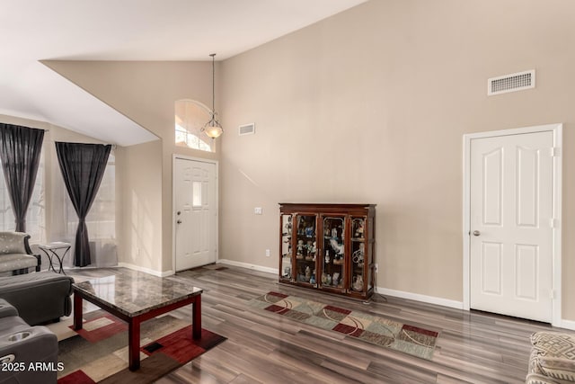 living room with an inviting chandelier, wood-type flooring, and high vaulted ceiling