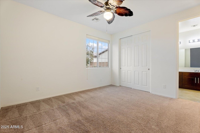 unfurnished bedroom featuring connected bathroom, light carpet, ceiling fan, and a closet