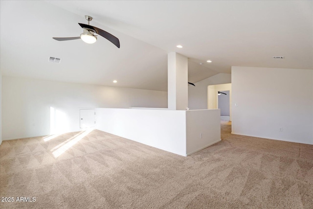 spare room with ceiling fan, vaulted ceiling, and light carpet