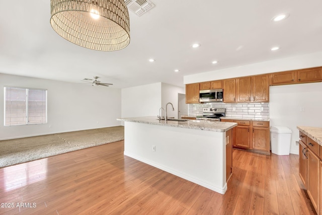 664 E Windsor Dr, Gilbert, AZ 85296 - kitchen featuring stainless steel appliances, a sink, brown cabinetry, a ceiling fan, and backsplash