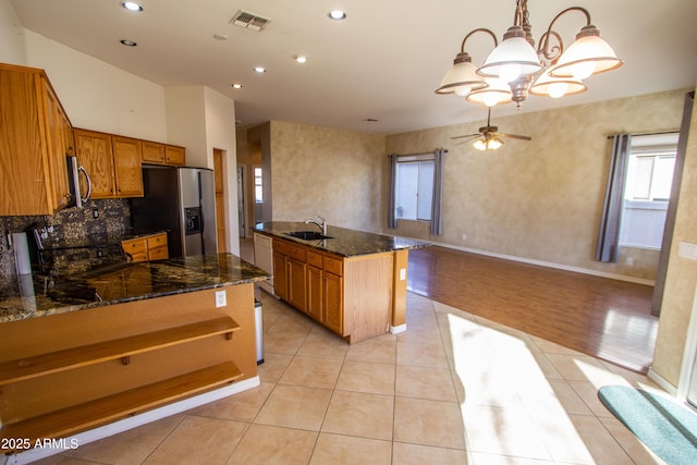 kitchen with appliances with stainless steel finishes, dark stone countertops, sink, hanging light fixtures, and light tile patterned floors