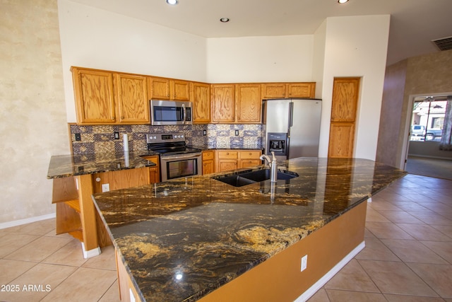 kitchen with a high ceiling, sink, appliances with stainless steel finishes, and light tile patterned flooring