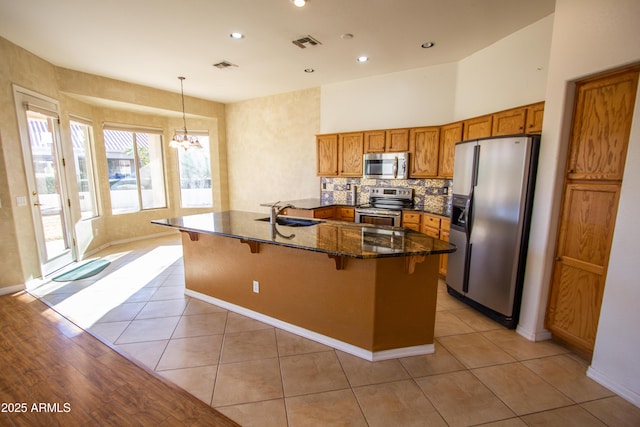 kitchen featuring an inviting chandelier, hanging light fixtures, a breakfast bar area, stainless steel appliances, and light tile patterned floors