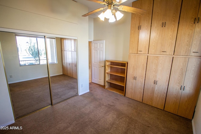 unfurnished bedroom with ceiling fan, a closet, dark colored carpet, and high vaulted ceiling