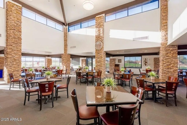 dining area with decorative columns and a high ceiling