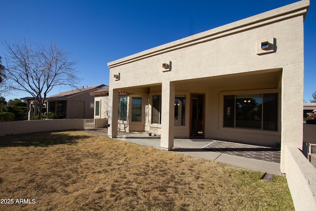 back of property with a lawn and a patio area