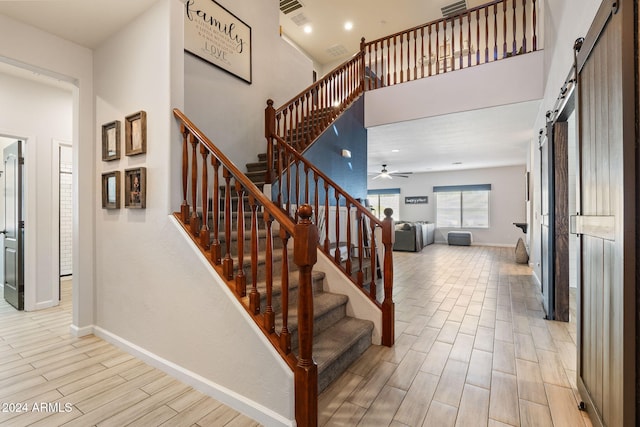 stairway with hardwood / wood-style floors, a barn door, and ceiling fan