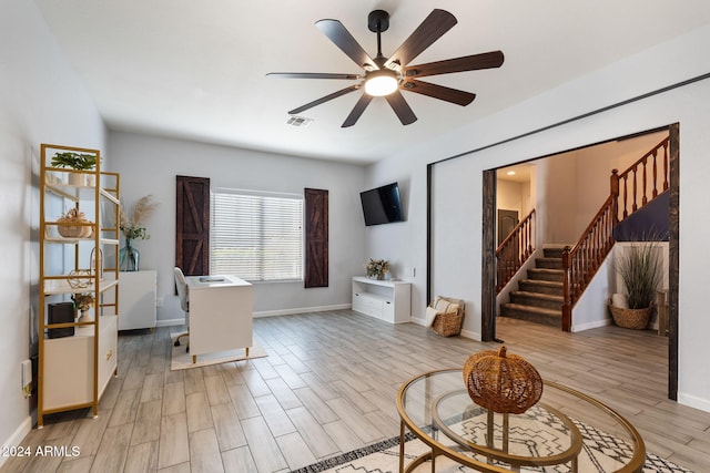 home office with light hardwood / wood-style flooring and ceiling fan