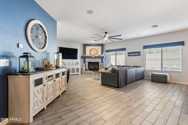 living room featuring light hardwood / wood-style flooring, a fireplace, and ceiling fan