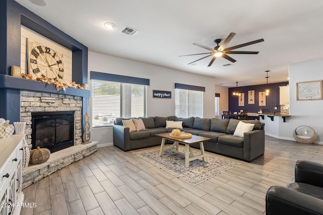 living room featuring a fireplace, light wood-type flooring, and ceiling fan