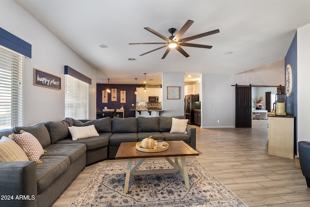 living room with a barn door, ceiling fan, a healthy amount of sunlight, and light hardwood / wood-style floors