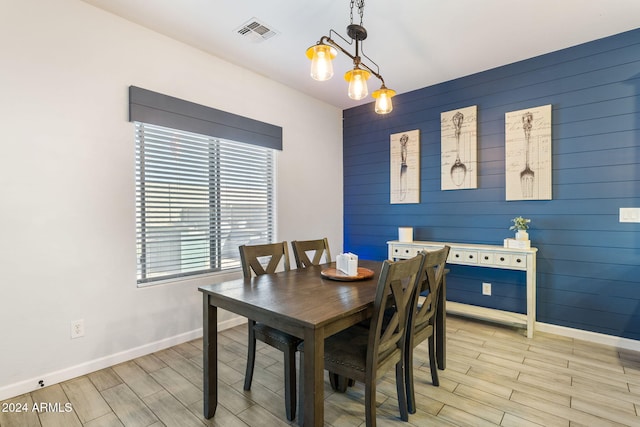 dining space with light hardwood / wood-style flooring and wooden walls