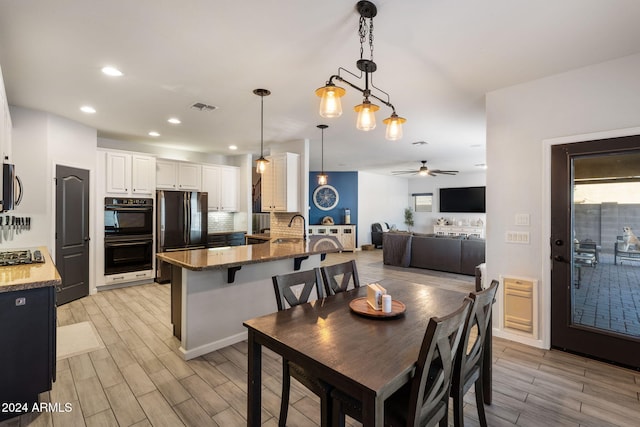 dining room with sink, light wood-type flooring, and ceiling fan