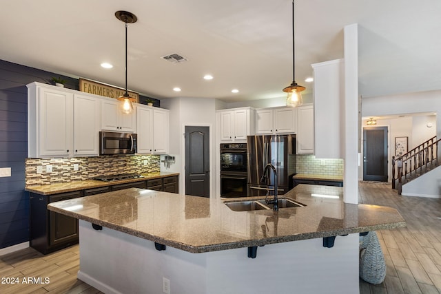 kitchen featuring white cabinetry, stainless steel appliances, light wood-type flooring, and dark stone counters