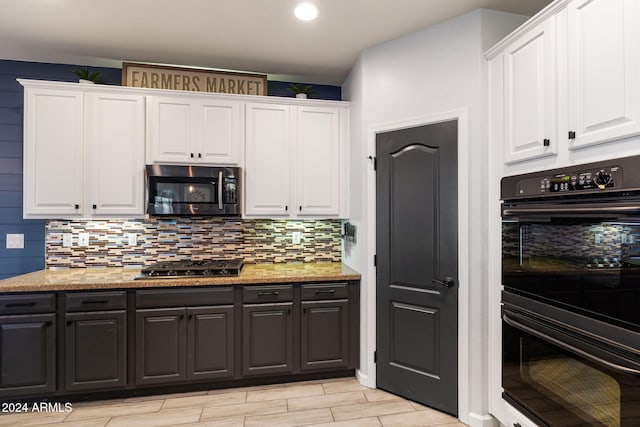 kitchen with light stone countertops, light wood-type flooring, white cabinetry, gas cooktop, and black double oven