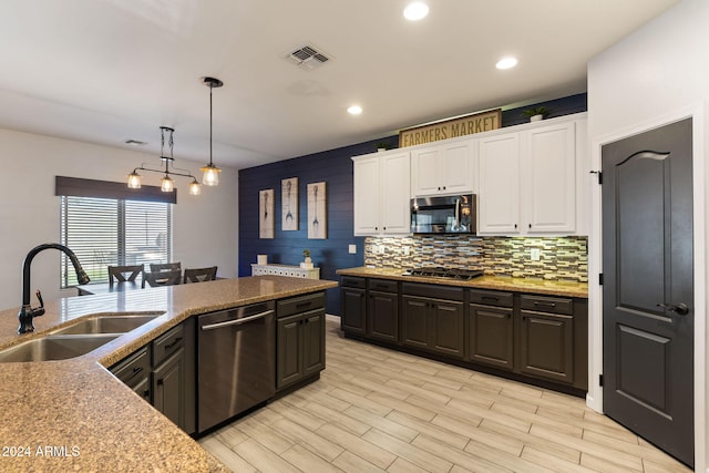 kitchen with white cabinets, hanging light fixtures, light wood-type flooring, sink, and stainless steel appliances