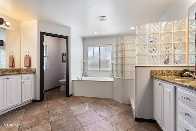 bathroom featuring toilet, vanity, tile patterned floors, and a bath